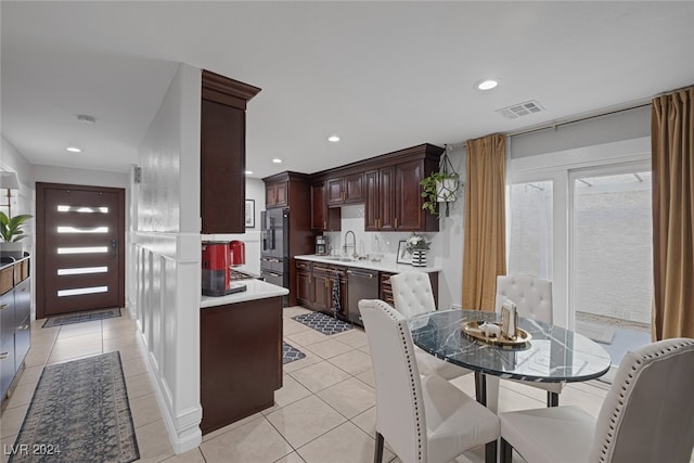 kitchen with stainless steel dishwasher, dark brown cabinetry, light tile patterned floors, and sink