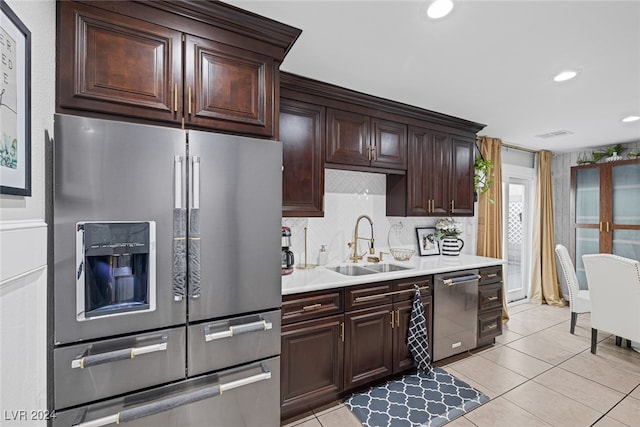 kitchen featuring light tile patterned floors, dark brown cabinetry, stainless steel appliances, and sink