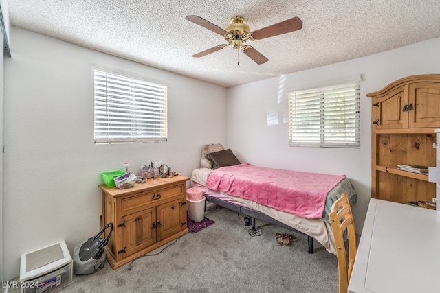 carpeted bedroom featuring multiple windows, a textured ceiling, and ceiling fan