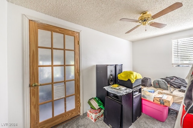 interior space featuring ceiling fan, carpet floors, and a textured ceiling