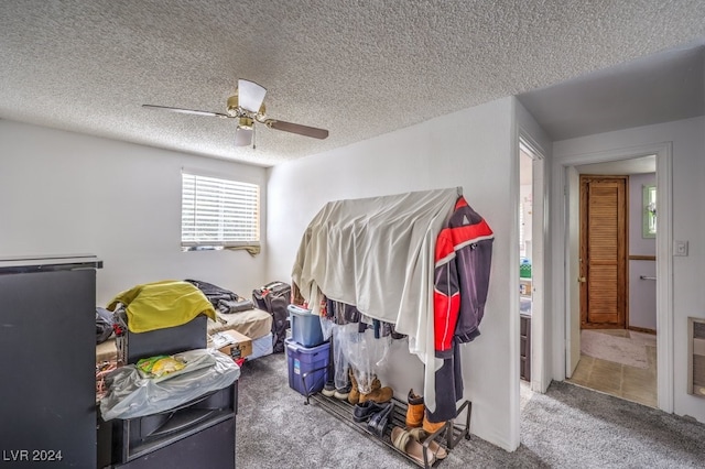 carpeted bedroom featuring ceiling fan and a textured ceiling