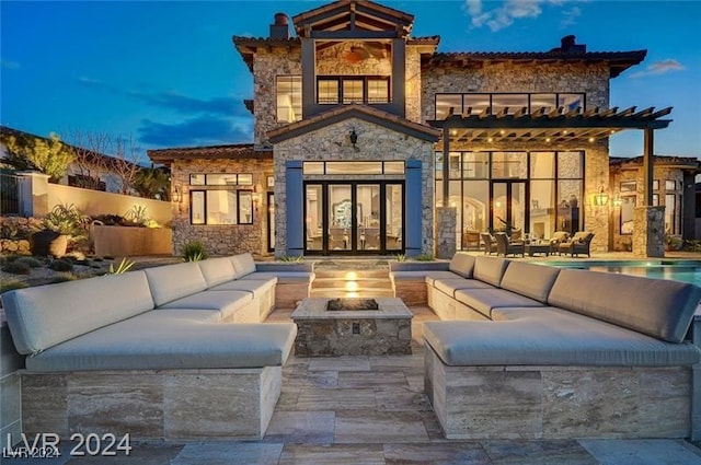 back house at dusk with french doors, a pergola, a patio, and an outdoor living space with a fire pit