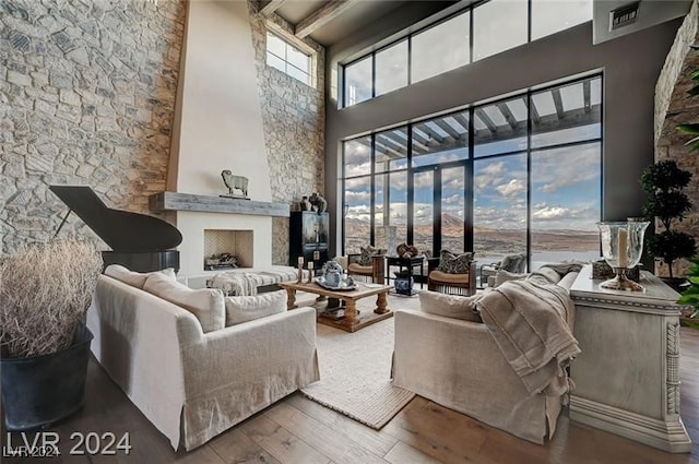 living room with beamed ceiling, a high ceiling, and hardwood / wood-style flooring