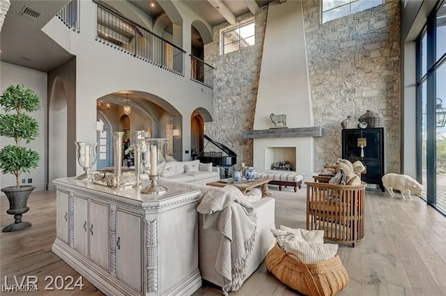 living room with a large fireplace, a towering ceiling, and light hardwood / wood-style floors