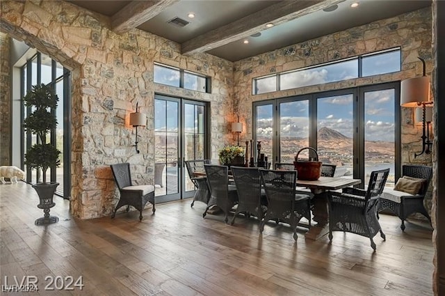 dining room featuring beamed ceiling, wood-type flooring, a towering ceiling, and a mountain view