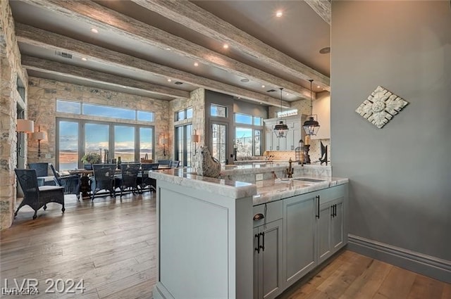 kitchen featuring kitchen peninsula, light wood-type flooring, plenty of natural light, and beamed ceiling