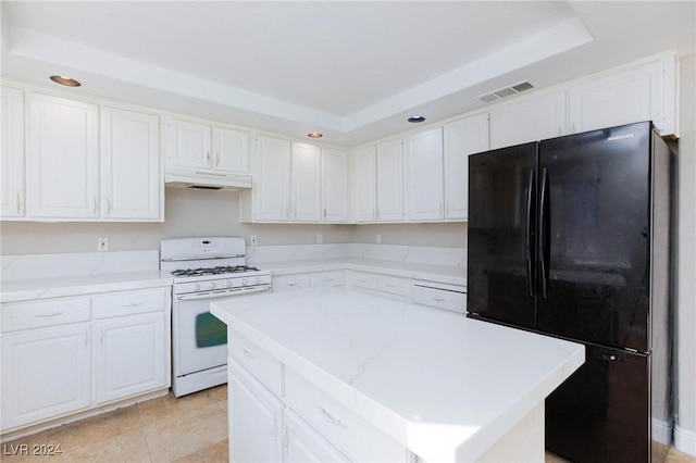 kitchen with white range with gas stovetop, white cabinetry, refrigerator, a raised ceiling, and a kitchen island