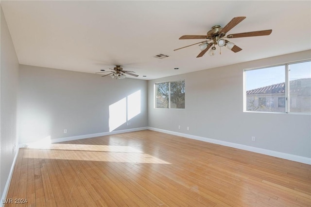 spare room with ceiling fan, a wealth of natural light, and light wood-type flooring