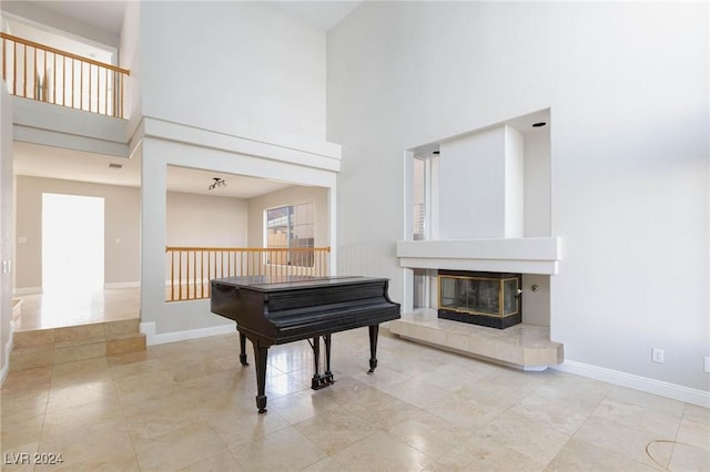 misc room with light tile patterned floors, a towering ceiling, and a tile fireplace