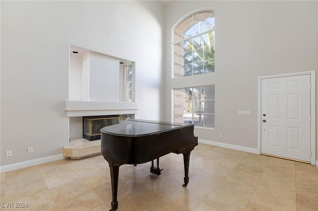 misc room with a towering ceiling and a tile fireplace