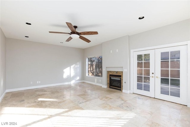 unfurnished living room featuring a high end fireplace, french doors, and ceiling fan