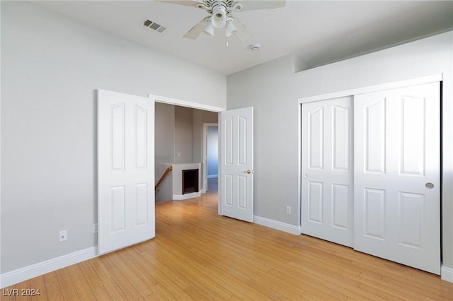 unfurnished bedroom with light wood-type flooring, ceiling fan, and a closet