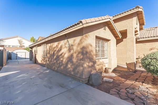 view of side of property with a storage unit and a patio