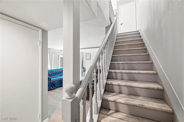 staircase with a textured wall and wood finished floors