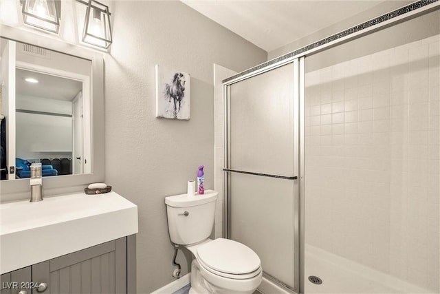 full bathroom featuring a textured wall, vanity, a shower stall, and toilet