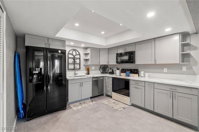 kitchen with a raised ceiling, a sink, black appliances, and open shelves