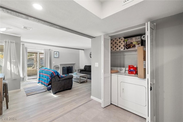 washroom featuring laundry area, light wood finished floors, visible vents, washer and dryer, and a fireplace