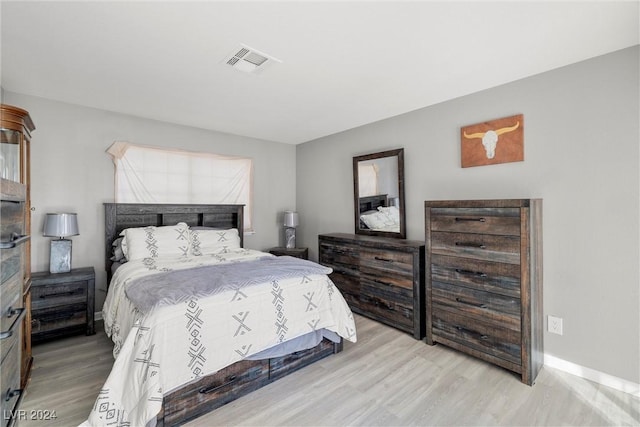 bedroom with light wood-type flooring, visible vents, and baseboards