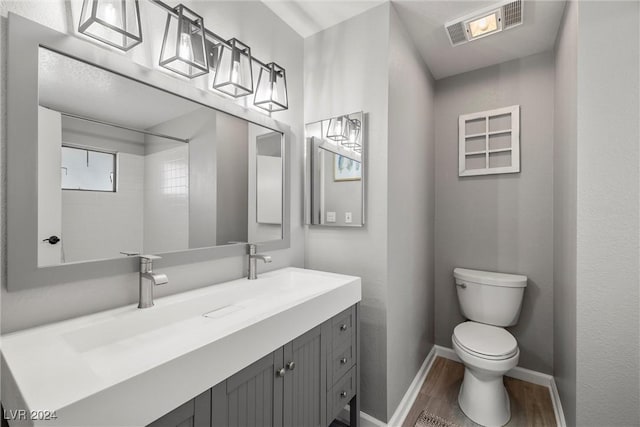 bathroom featuring toilet, wood finished floors, vanity, visible vents, and baseboards