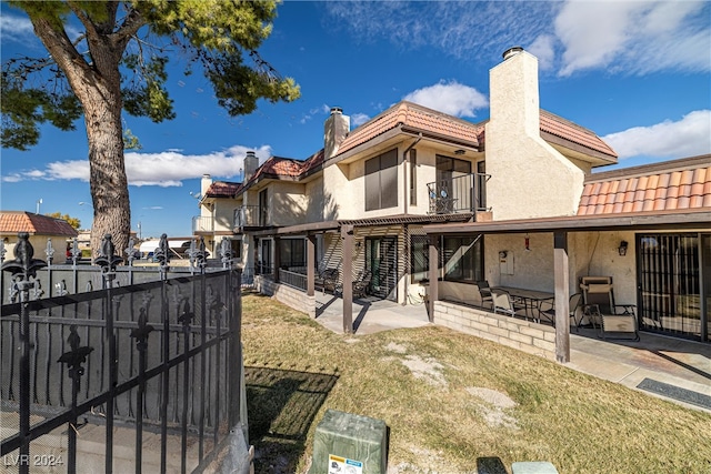 back of property with a chimney, fence, a yard, a patio area, and stucco siding