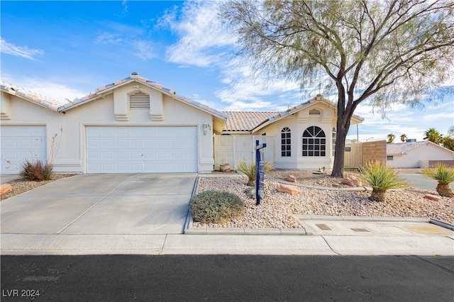 view of front of home featuring a garage, driveway, fence, and stucco siding