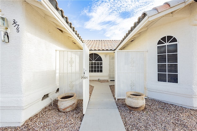 entrance to property featuring a tiled roof, crawl space, and stucco siding