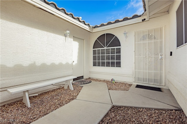 view of exterior entry featuring a tile roof and stucco siding