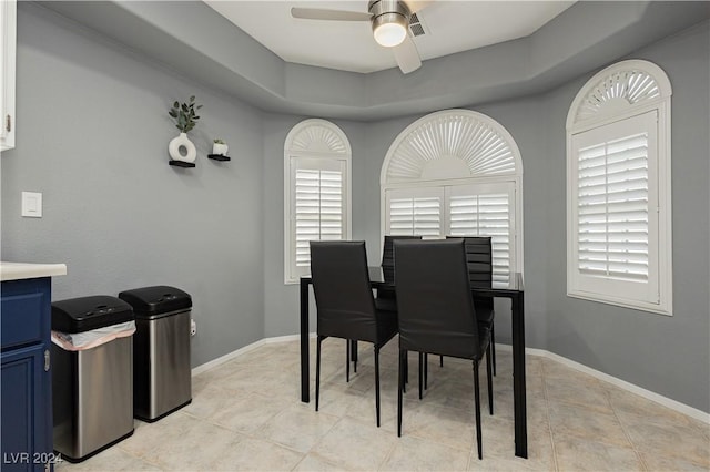 dining room featuring visible vents, a raised ceiling, a ceiling fan, and baseboards