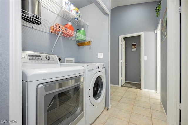 clothes washing area featuring laundry area, light tile patterned floors, baseboards, and washer and clothes dryer