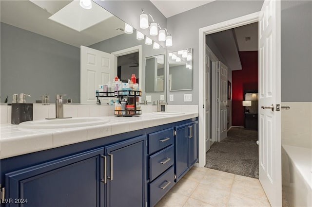 full bathroom featuring double vanity, a skylight, tile patterned flooring, and a sink