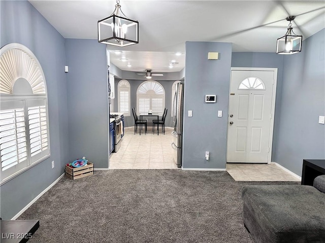 foyer featuring light tile patterned floors, baseboards, a ceiling fan, and light colored carpet