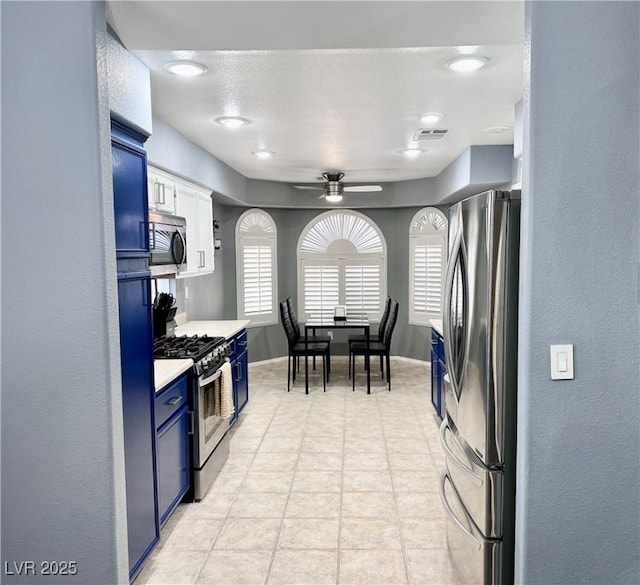 kitchen featuring visible vents, a ceiling fan, appliances with stainless steel finishes, blue cabinets, and light countertops