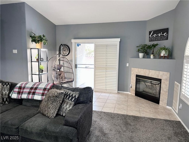 tiled living area featuring carpet, a tiled fireplace, and baseboards