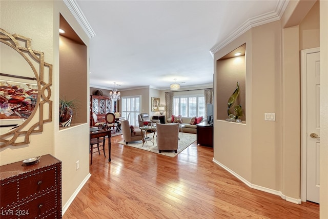 living room with light wood-type flooring, ornamental molding, and a notable chandelier