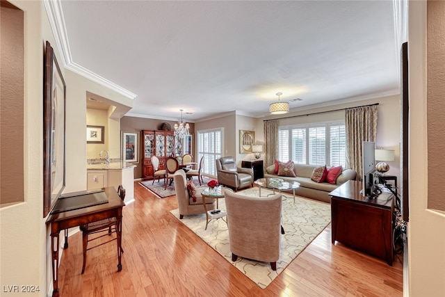 living room featuring light wood-type flooring, an inviting chandelier, and ornamental molding