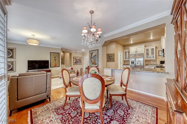 dining space featuring crown molding, light wood-type flooring, and an inviting chandelier