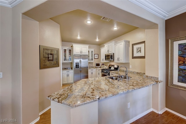 kitchen featuring white cabinets, sink, light stone countertops, kitchen peninsula, and stainless steel appliances