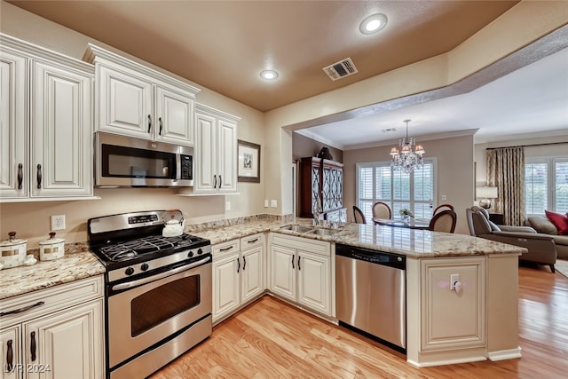 kitchen featuring a notable chandelier, crown molding, kitchen peninsula, and stainless steel appliances