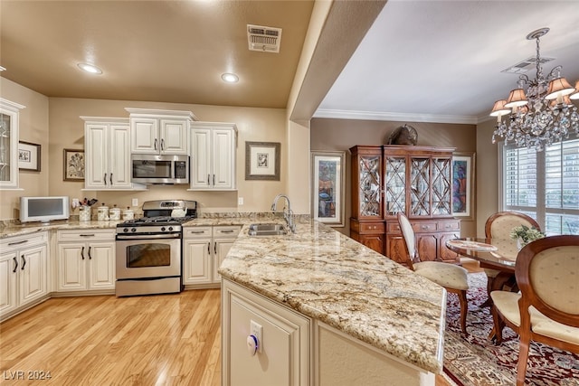 kitchen featuring appliances with stainless steel finishes, light wood-type flooring, crown molding, sink, and a chandelier