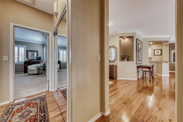 hallway featuring ornamental molding and light hardwood / wood-style flooring