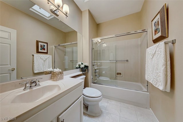 full bathroom featuring a skylight, tile patterned flooring, bath / shower combo with glass door, toilet, and vanity