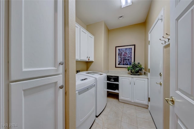 laundry area featuring cabinets, light tile patterned floors, and washer and clothes dryer