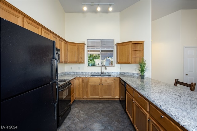 kitchen with sink, light stone counters, kitchen peninsula, a breakfast bar area, and black appliances