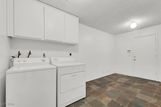 clothes washing area featuring a textured ceiling, baseboards, washer and dryer, cabinet space, and stone finish flooring