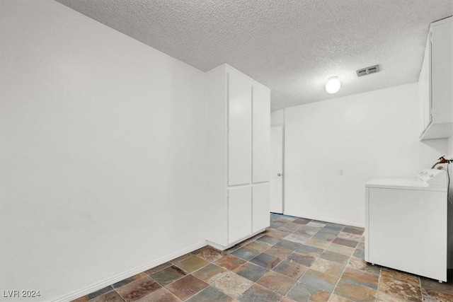 interior space featuring visible vents, baseboards, cabinet space, stone finish flooring, and washer / clothes dryer