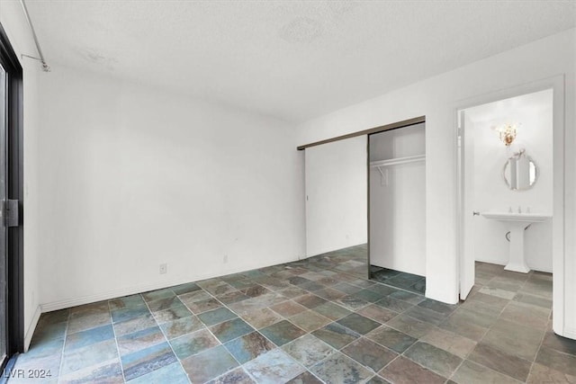 unfurnished bedroom with a textured ceiling, stone finish floor, and a closet