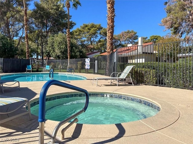 view of swimming pool featuring a community hot tub and fence