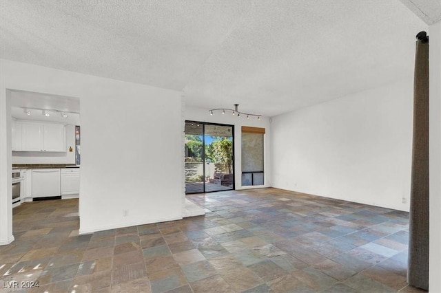 spare room featuring a textured ceiling, stone finish flooring, and baseboards