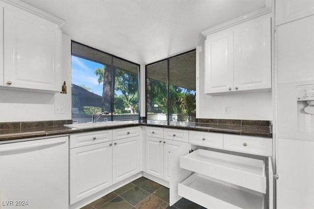 kitchen featuring dark countertops, white dishwasher, and white cabinetry