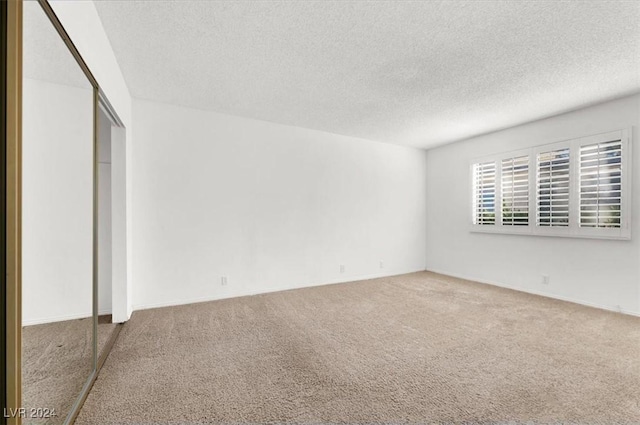 carpeted empty room with a textured ceiling